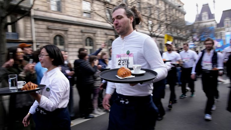 Pic: AP Waiters carry trays with a cup of coffee, a croissant and a glass of water as they take part in a waiter's run through the streets of Paris, Sunday, March 24, 2024. (AP Photo/Christophe Ena)
